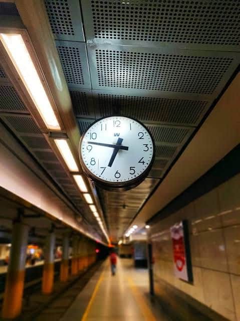 Vista frontal de un reloj exterior iluminado en el Metro Rail de Delhi