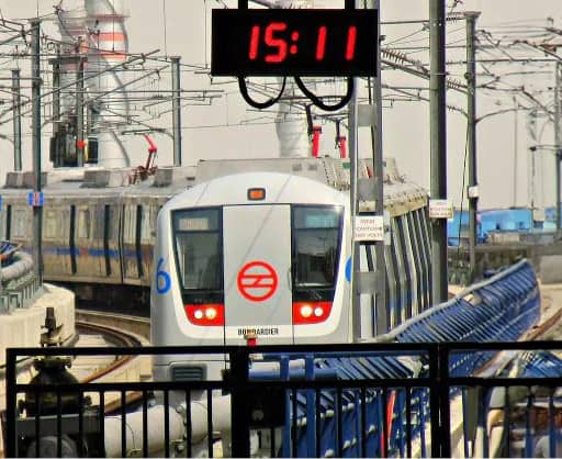 Train arriving at station with digital clock with red display in the foreground