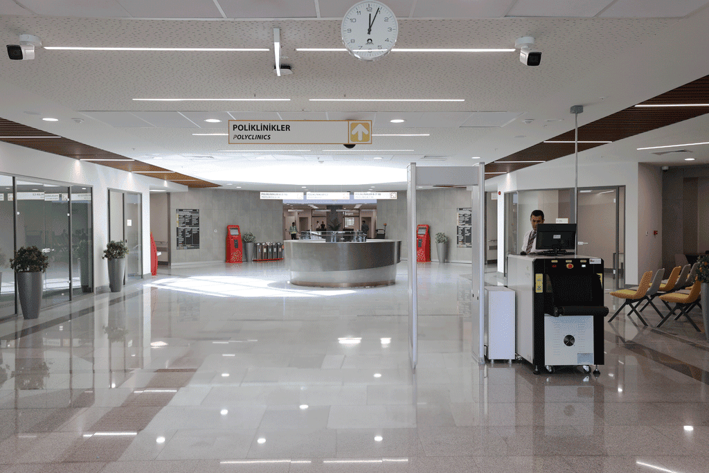 A corridor with a shiny white floor and analogue clocks