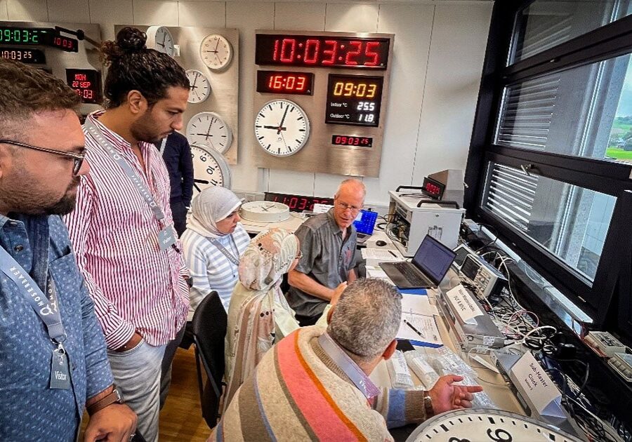 Engineers and project representatives observe live testing of master and slave clocks during the Factory Acceptance Test (FAT) for Egypt’s High-Speed Rail project at Moser-Baer headquarters, with synchronized time displays visible in the background.