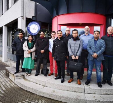 Délégation de haut niveau représentant les responsables du métro de Dhaka à Sumiswald avec les membres de l'équipe MOBATIME devant le bâtiment MOBATIME, horloges analogiques derrière à gauche.