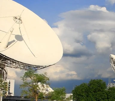 Antenas parabólicas apuntando a un cielo despejado, reflejando la distribución horaria de MOBATIME para telecocomunicaciones