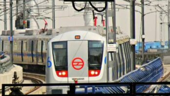 Train arriving at station with digital clock with red display in the foreground